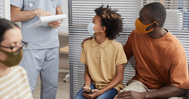 Black man and child wear masks in a doctor's waiting room
