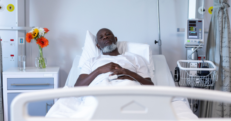 Portrait of african american male patient lying on hospital bed looking to camera