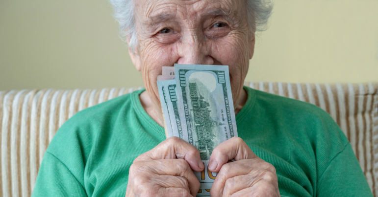 a happy senior woman holding american dollars